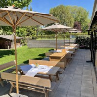 Tische für je 6 Personen mit Sonnenschutz und Blick auf den Garten im Restaurant Erber nahe Garching