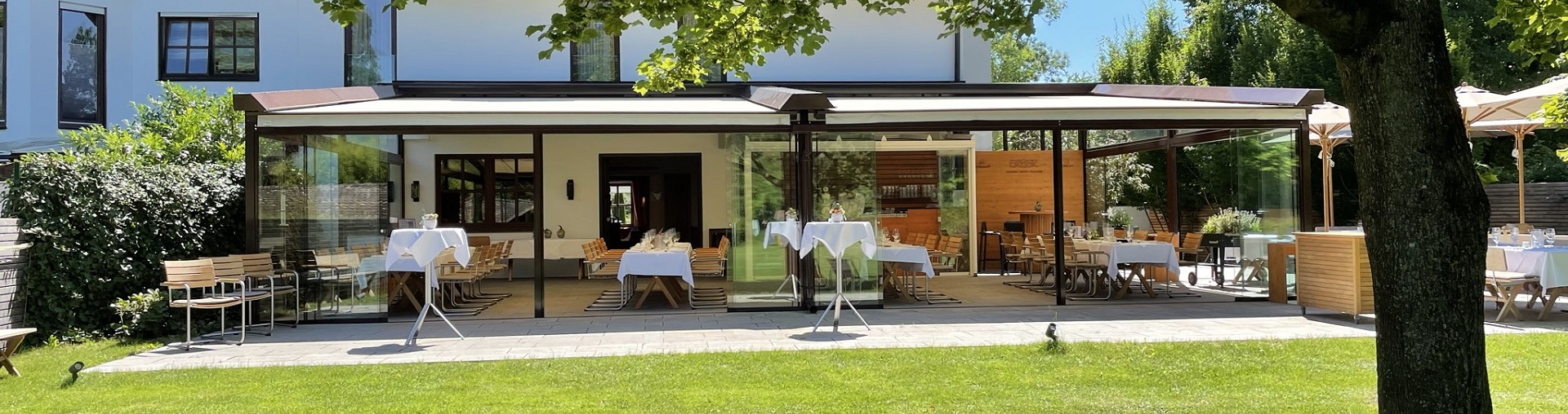 Sommerevent auf einer Terrasse mit schön gedeckten Tischen, Sonnenschirmen und Bar in Ismaning bei München